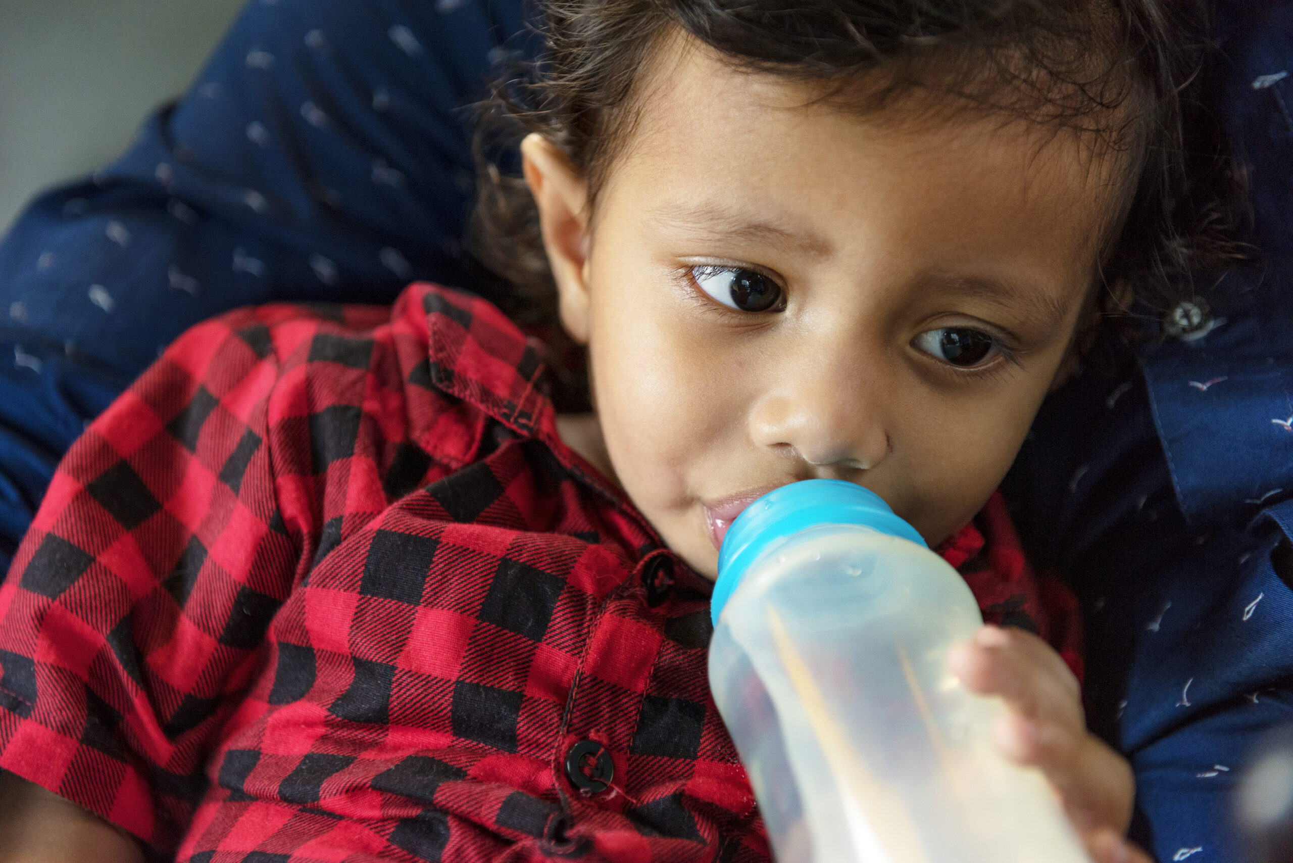 Young boy drinking milk from bottle even though he should ween off a bottle