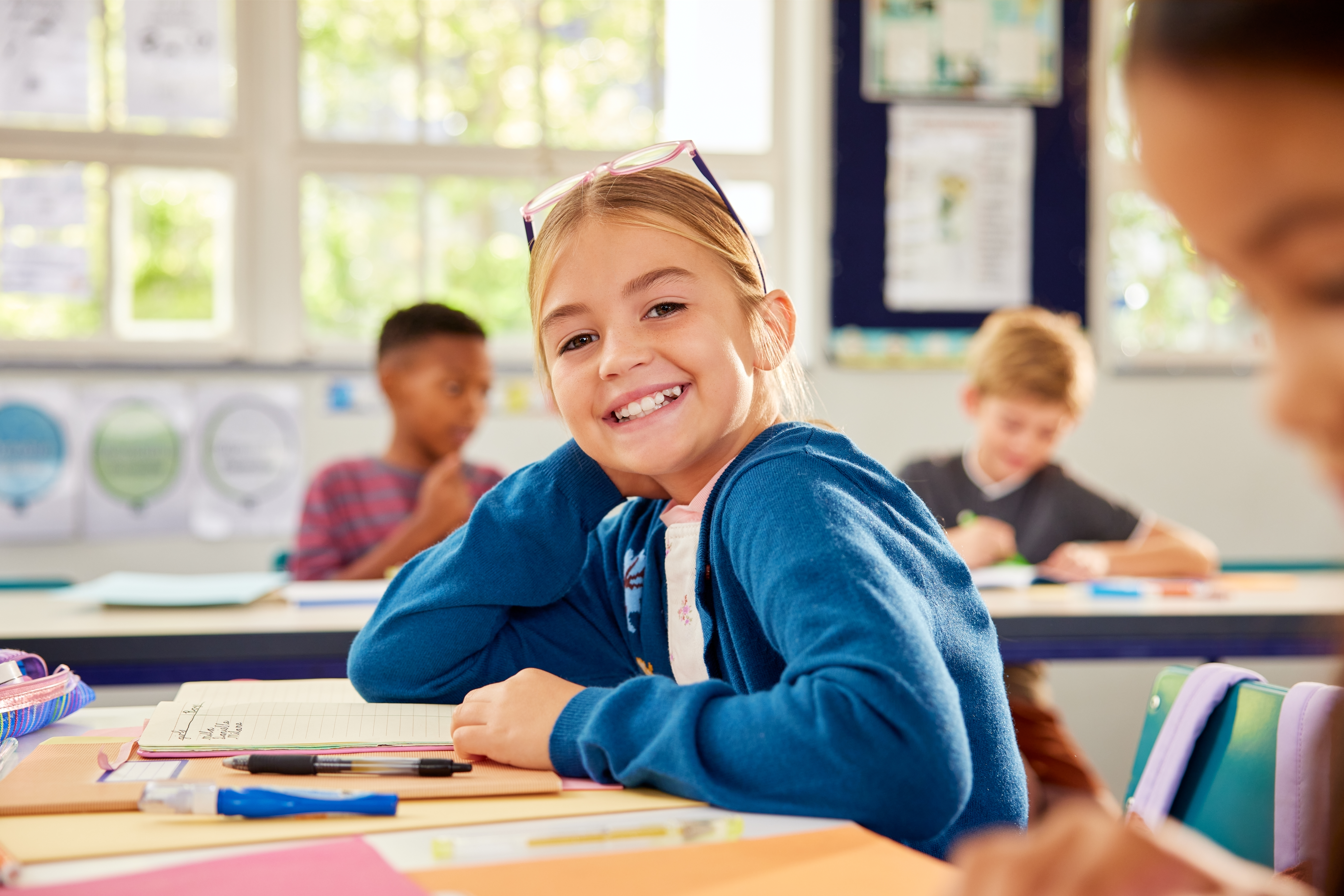 A schoolgirl smiling at her desk after getting therapy treatments for her OMD